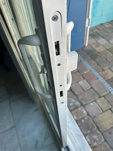 Close-up of a white sliding door handle and mortise lock face plate.