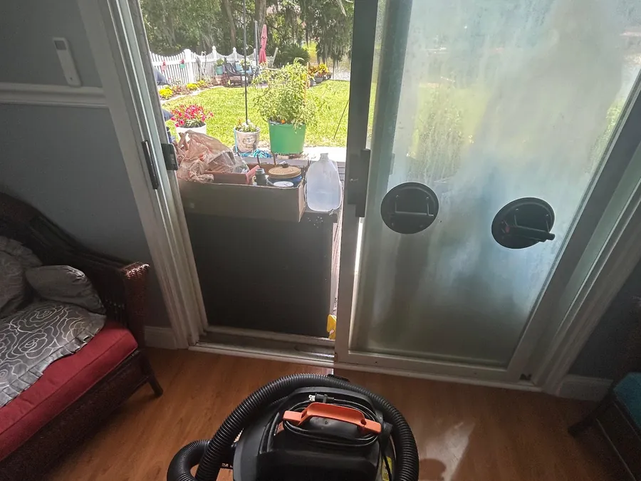 A sliding door opening with the panel removed, a shop vacuum and tools on the floor.