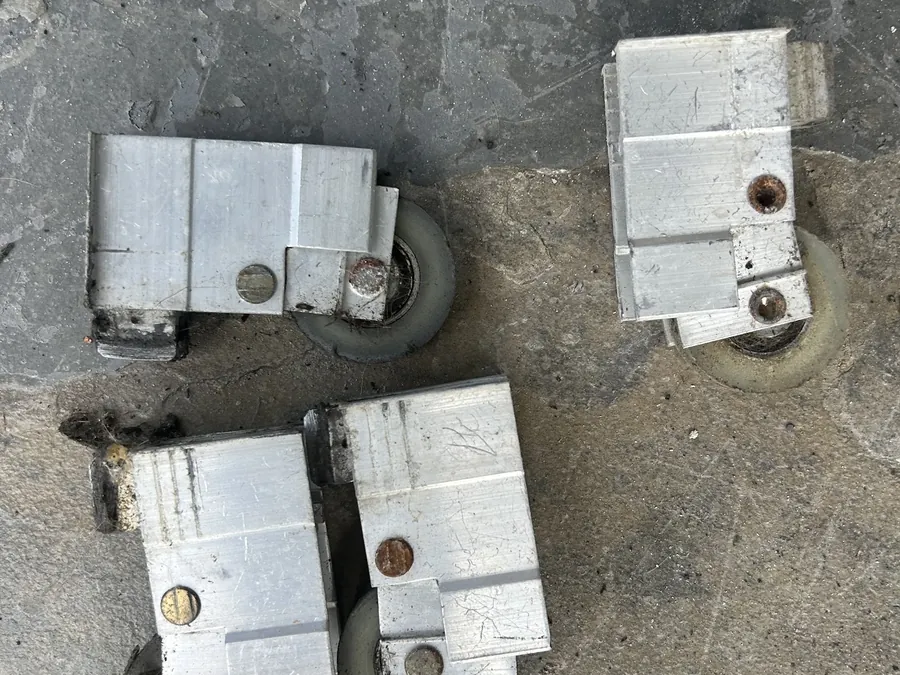 Four used aluminium roller carriages removed from a four-panel sliding door.